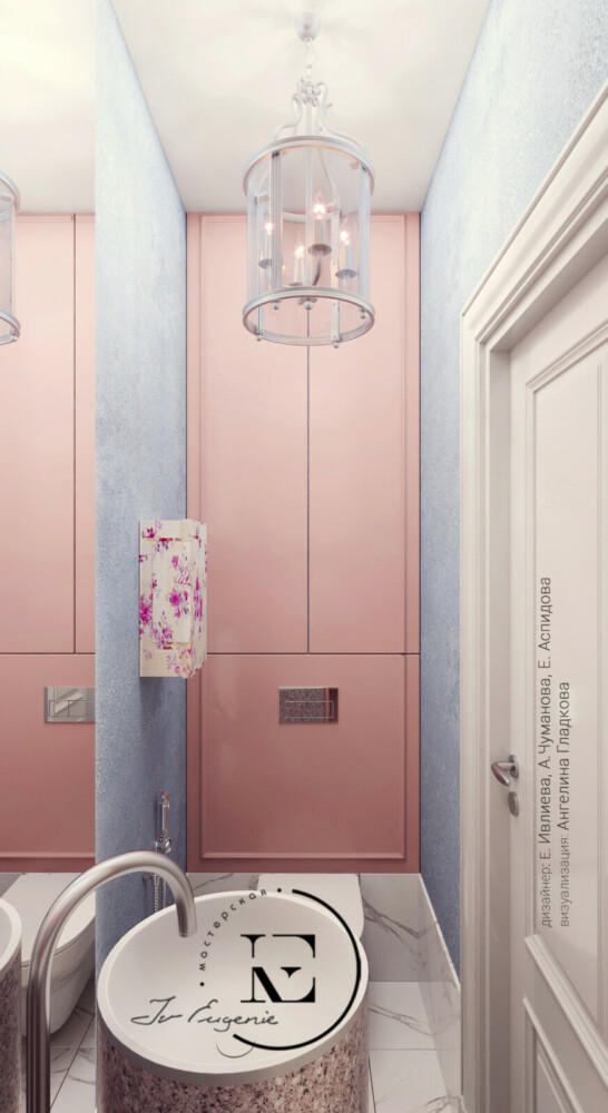 Санузел достаточно маленький по площади. На полу мраморная плитка, что и в ванной, плюс один ряд выложен на стену до уровня унитаза. Над инсталляцией стены выкрашены в розовый цвет с отделкой молдингом. Скрытая система хранения выполнена в том же цвете.
Молдинги используются, как декоративная графика. Дверцы шкафа открываются от нажатия.
Стены выкрашены в той же технике Амбре, что и в холле (это декоративная штукатурка с перламутром и песочком) снизу темно- голубой, а сверху светло-бирюзовый.
Люстра изящная и красивая, как и во всей квартире.